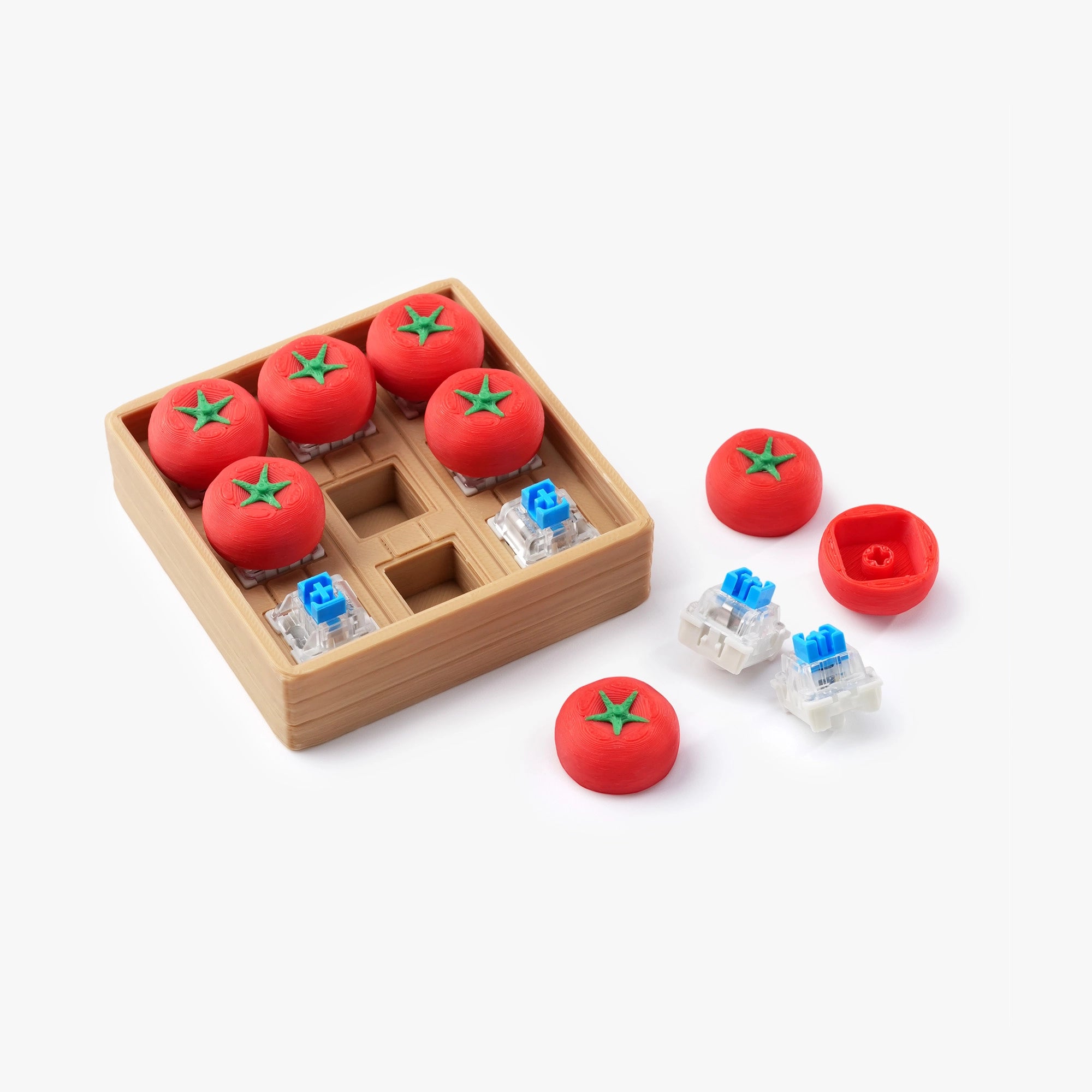 3D printed tomato clicker pieces beside wooden tray